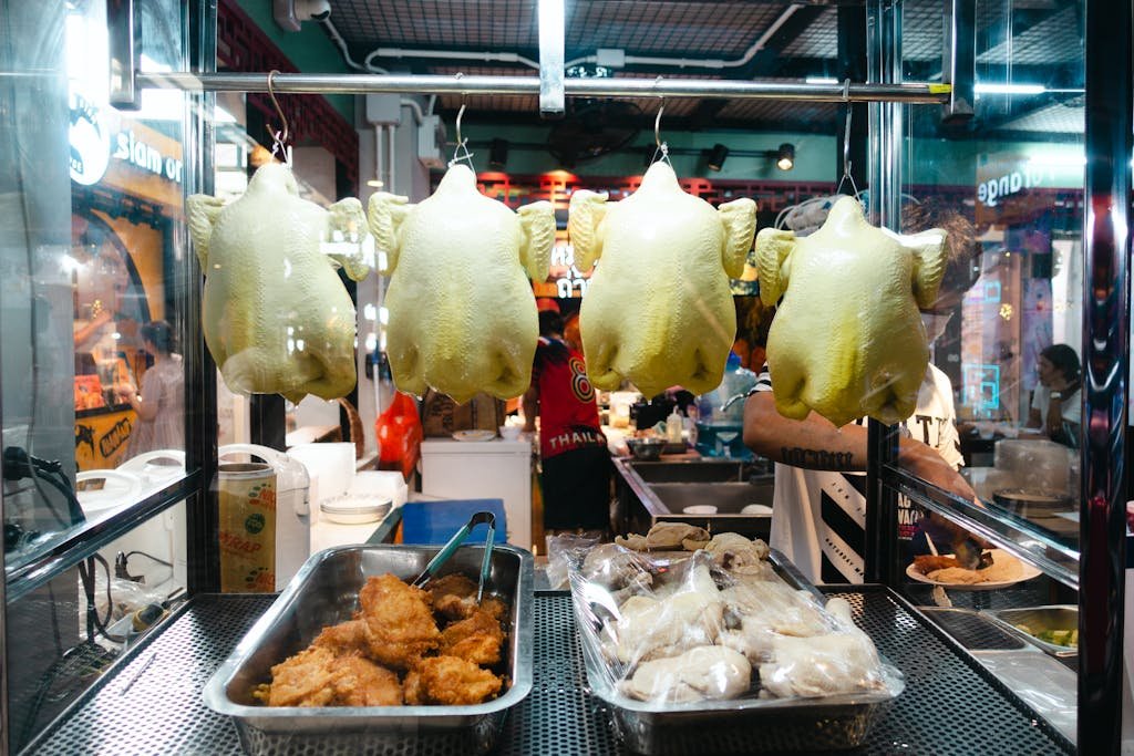 A vibrant display of rotisserie chickens in a Thai street market booth.